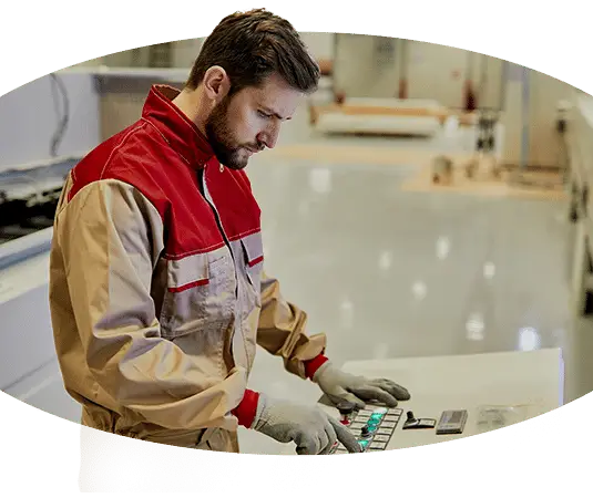 Ein Mann mit einem Kranführerjob, der einen Computer in einer Fabrik bedient.