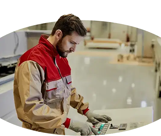 Ein Mann mit einem Kranführerjob, der einen Computer in einer Fabrik bedient.